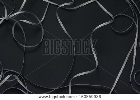 Frame with silver ribbon scrollwork. Decor for celebration. Black background, top view, flat lay, copy space