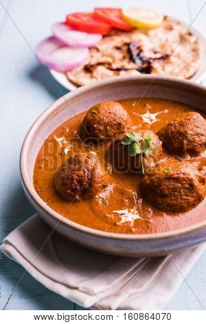 malai kofta curry - classic North Indian dish. vegetarian alternative to meatballs served with tandoori roti or indian bread and green salad, selective focus
