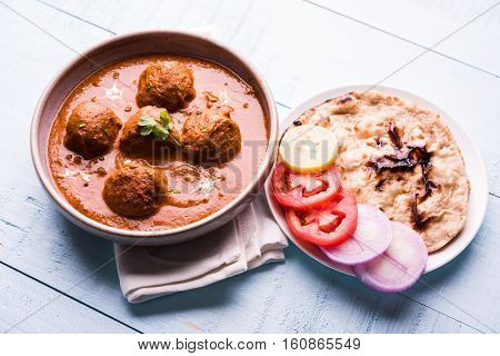 malai kofta curry - classic North Indian dish. vegetarian alternative to meatballs served with tandoori roti or indian bread and green salad, selective focus