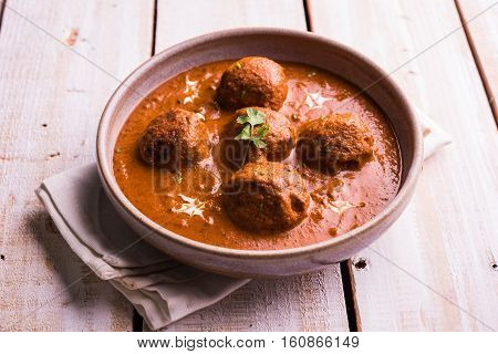 malai kofta curry - classic North Indian dish. vegetarian alternative to meatballs served with tandoori roti or indian bread and green salad, selective focus