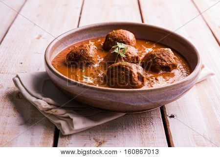malai kofta curry - classic North Indian dish. vegetarian alternative to meatballs served with tandoori roti or indian bread and green salad, selective focus
