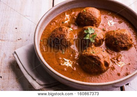 malai kofta curry - classic North Indian dish. vegetarian alternative to meatballs served with tandoori roti or indian bread and green salad, selective focus
