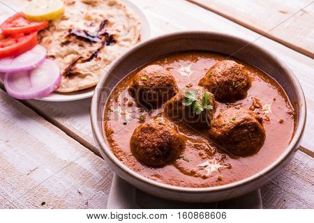 malai kofta curry - classic North Indian dish. vegetarian alternative to meatballs served with tandoori roti or indian bread and green salad, selective focus