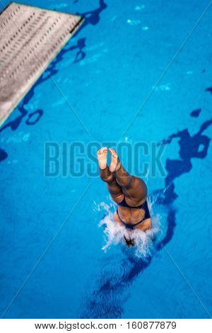 Female diver jumping into the pool from diving board