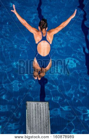Female diver jumping into the pool from diving board