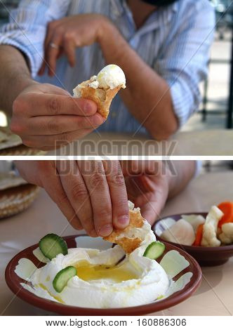 A man dipping pita bread in labneh and offering it.