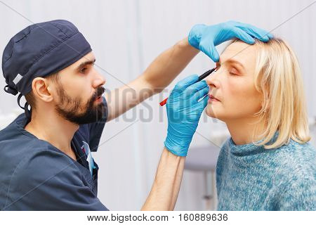 marking the face of an elderly woman old of plastic surgery at a reception at the doctor