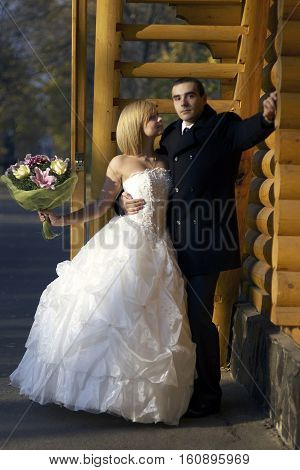 Beautiful wedding couple hold each other hand and embracing in autumn park under the sunbeam wooden sunny background.A young couple in love.