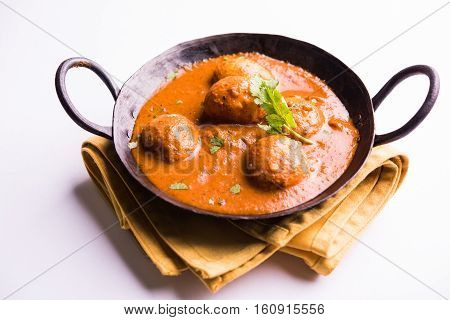 Freshly cooked spicy potato curry in frying pan or Hot and spicy Dum aloo served with tandoori roti or naan or indian bread or chapati and green salad, selective focus