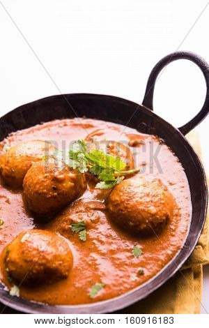 Freshly cooked spicy potato curry in frying pan or Hot and spicy Dum aloo served with tandoori roti or naan or indian bread or chapati and green salad, selective focus