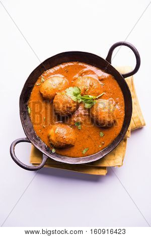 Freshly cooked spicy potato curry in frying pan or Hot and spicy Dum aloo served with tandoori roti or naan or indian bread or chapati and green salad, selective focus