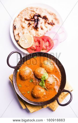 Freshly cooked spicy potato curry in frying pan or Hot and spicy Dum aloo served with tandoori roti or naan or indian bread or chapati and green salad, selective focus