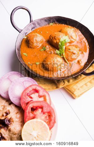Freshly cooked spicy potato curry in frying pan or Hot and spicy Dum aloo served with tandoori roti or naan or indian bread or chapati and green salad, selective focus