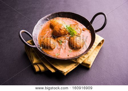 Freshly cooked spicy potato curry in frying pan or Hot and spicy Dum aloo served with tandoori roti or naan or indian bread or chapati and green salad, selective focus