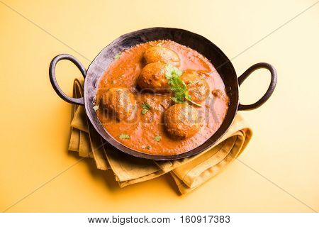 Freshly cooked spicy potato curry in frying pan or Hot and spicy Dum aloo served with tandoori roti or naan or indian bread or chapati and green salad, selective focus