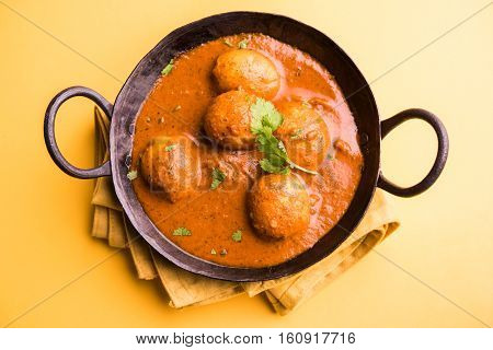 Freshly cooked spicy potato curry in frying pan or Hot and spicy Dum aloo served with tandoori roti or naan or indian bread or chapati and green salad, selective focus
