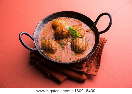 Freshly cooked spicy potato curry in frying pan or Hot and spicy Dum aloo served with tandoori roti or naan or indian bread or chapati and green salad, selective focus