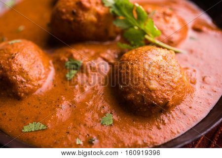 Freshly cooked spicy potato curry in frying pan or Hot and spicy Dum aloo served with tandoori roti or naan or indian bread or chapati and green salad, selective focus