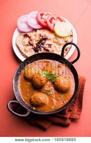 Freshly cooked spicy potato curry in frying pan or Hot and spicy Dum aloo served with tandoori roti or naan or indian bread or chapati and green salad, selective focus