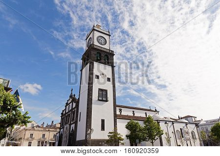 Saint Sabastian church with clock tower in Ponta Delgada on Sao Miguel Island in Azores Portugal. Beautiful church in early morning under white clouds.