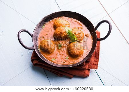 Freshly cooked spicy potato curry in frying pan or Hot and spicy Dum aloo served with tandoori roti or naan or indian bread or chapati and green salad, selective focus