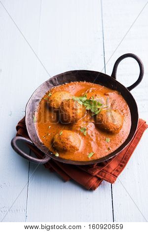 Freshly cooked spicy potato curry in frying pan or Hot and spicy Dum aloo served with tandoori roti or naan or indian bread or chapati and green salad, selective focus