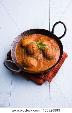 Freshly cooked spicy potato curry in frying pan or Hot and spicy Dum aloo served with tandoori roti or naan or indian bread or chapati and green salad, selective focus