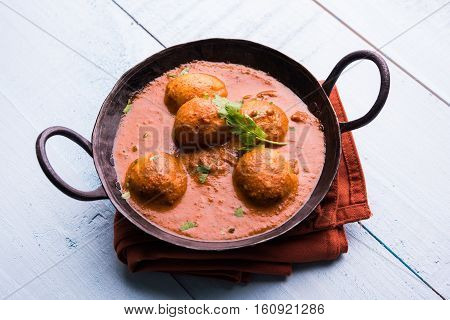 Freshly cooked spicy potato curry in frying pan or Hot and spicy Dum aloo served with tandoori roti or naan or indian bread or chapati and green salad, selective focus