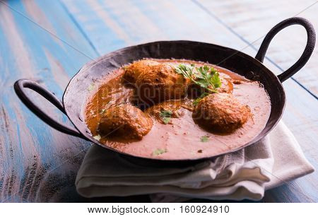 Freshly cooked spicy potato curry in frying pan or Hot and spicy Dum aloo served with tandoori roti or naan or indian bread or chapati and green salad, selective focus
