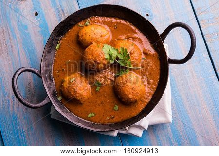 Freshly cooked spicy potato curry in frying pan or Hot and spicy Dum aloo served with tandoori roti or naan or indian bread or chapati and green salad, selective focus