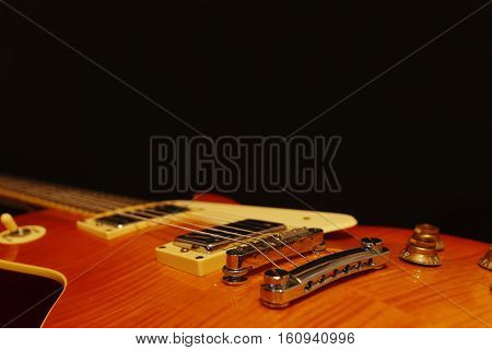Solid body electric jazz guitar closeup on the black background with plenty of copy space. Selective focus.