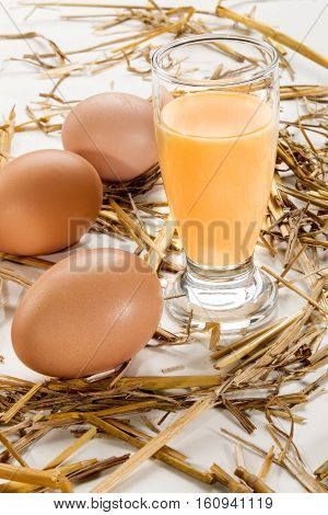 home made advocaat in a glass and eggs around with straw