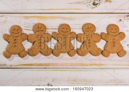 Christmas smiling gingerbread men men and women on rustic wooden background