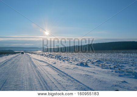 Winter snowy road and sunrise. The sky and the sun.