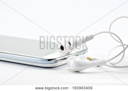 The white smart phone and white earphones on the white background isolate.