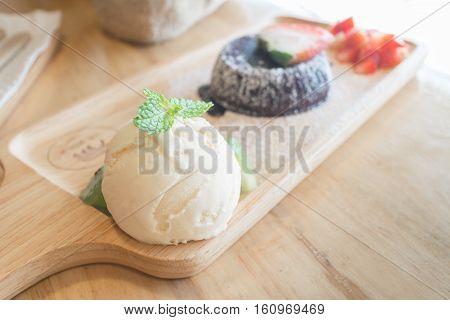chocolate lava cake with vanilla ice cream and strawberry. chocolate lava on wood plate. Hot chocolate pudding with fondant centre.(selective focus)