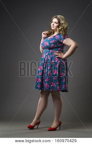 Young beautiful blonde plus size model in dress and shoes xxl woman on gray studio background full length portrait