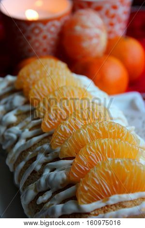 Biscuit and Cake with Mandarin and Whipped Cream. А kandle and mandarins are on the table.