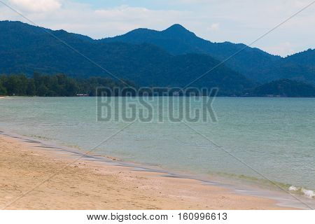 The white sand and blue sea on the background of beautiful mountains
