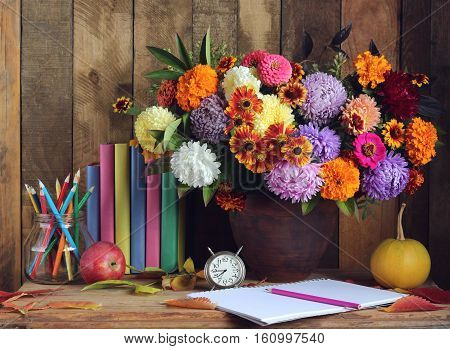 Bouquet pumpkins pencils Apple books and clock on the table. Still life. Back to school. Teacher's Day. September 1.