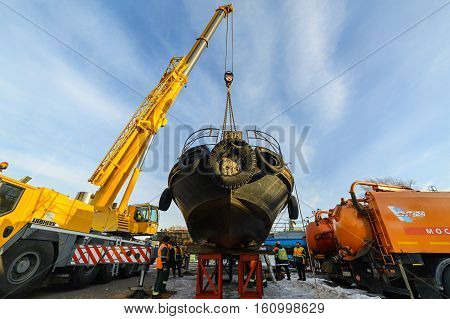 MOSCOW, RUSSIA - NOVEMBER 11, 2016: State Unitary Enterprise Mosvodostok performs recovery vessels on coastal winter parking. Truck Crane sets the ship on steel supports.