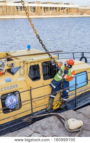 MOSCOW, RUSSIA - NOVEMBER 11, 2016: State Unitary Enterprise Mosvodostok performs recovery vessels on coastal winter parking. One worker slingers hooked to the vehicle chain slings.