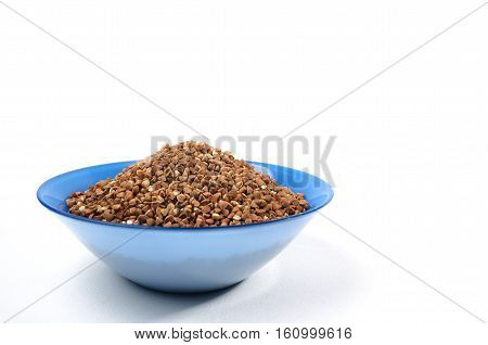 Buckwheat grains in Blue bowl from above isolated on white background. On left side