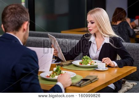 A woman and a man on a business lunch in a restaurant. exploring work on the tablet screen