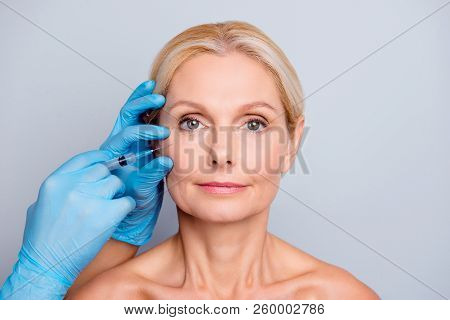 Portrait Of Calm Serious Charming Aged Woman With Wrinkle Getting Injection In Cheek In Professional