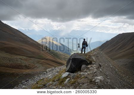 Landscape photographer with camera and tripod in the mountains. View of the Svan range. Main Caucasian ridge. Samegrelo-zemo Svaneti, Georgia 