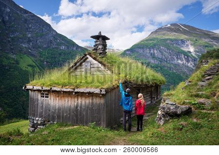 Kagefla - mountain farms with turf houses along the Geirangerfjorden fjord. Tourist attraction near Geiranger city, Norway. Travelers visiting traditional Scandinavian architecture