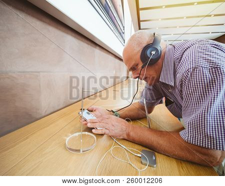 Strasbourg, France - Sep 21, 2018: Side View Of Funny Curious Senior Man Testing Apple Beats By Dr D