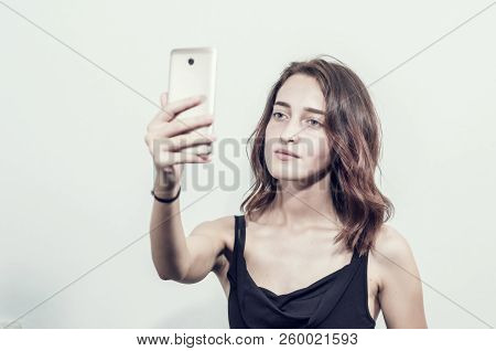 Beautiful Young Girl Holding A Phone. Makes Photos, Selfies