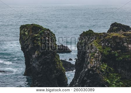 Mossy Cliffs In Front Of Blue Ocean In Arnarstapi, Iceland On Cloudy Day